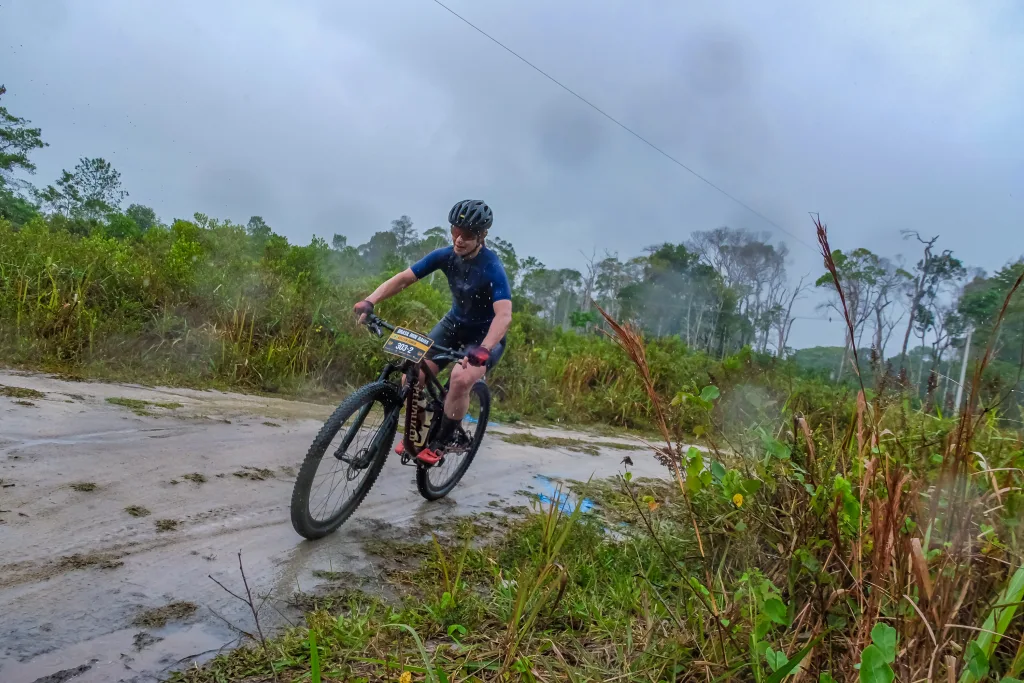 Woman mountain biking on dirt road in the rain