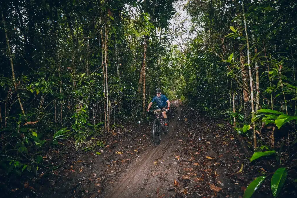 Woman on mountain bike riding trough jungle in the rain